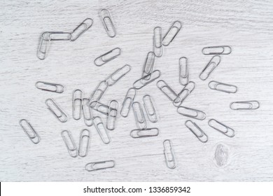 Paper clips scattered on a gray wooden surface - Powered by Shutterstock