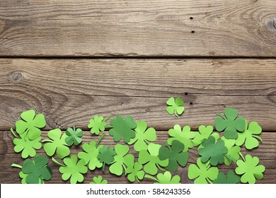 Paper clover leaves on the old wooden background. Lucky shamrock, St.Patrick's day holiday symbol. Space for text, top view.