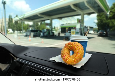 Paper Coffee Cup And Doughnut On Car Dashboard At Gas Station