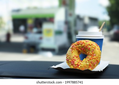 Paper Coffee Cup And Doughnut On Car Dashboard At Gas Station