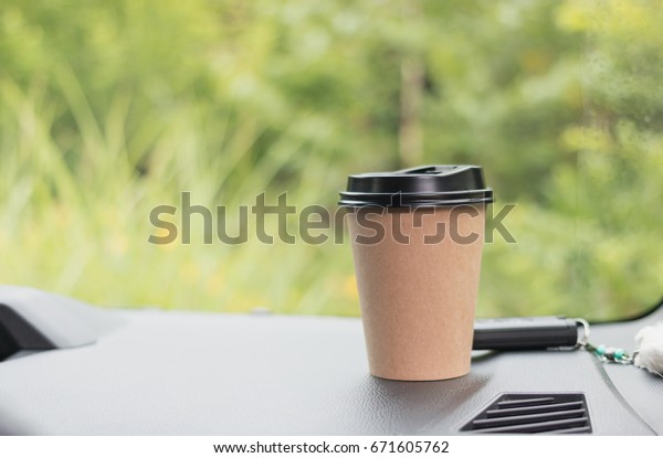 paper coffee cup on dashboard car and car key\
blurred green background