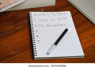 A paper containing "Notes Today" in a notebook, On a wooden table.