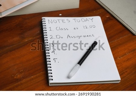 A paper containing "Notes Today" in a notebook, On a wooden table.