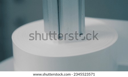 Paper converting machine at a paper manufacturing plant. Commercial mass production at automatic conveyor belt of factory line. Close up, depth of field