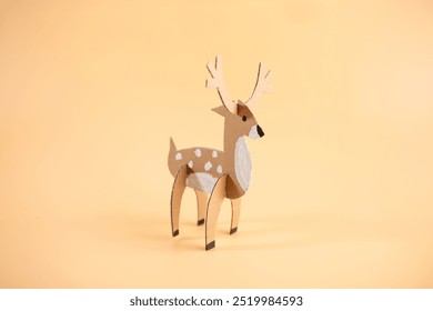 paper craft model of a deer on a plain orange background, recycling concept, fun project for anyone interested in crafts or animal models,