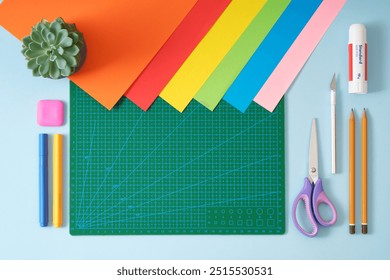 Paper crafts work table top view. Tools green cutting mat, scissors, office knife, pencil, glue, colored paper. A place for your text. - Powered by Shutterstock