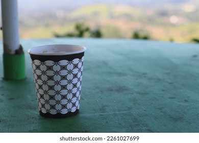 Paper cup with batik patterns from coffee drinks on a table with green views of the mountains