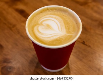 Paper cup of cafe latte on wooden table background. Art style hot coffee. A latte is a coffee drink made with espresso and steamed milk.