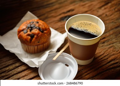 Paper cup of coffee and cake on wooden background