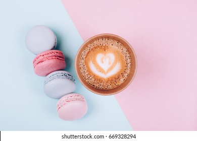 Paper Cup Of Coffee To Go With Macaron On Pink And Blue Background From Above, Flat Lay