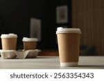 Paper cup on light wooden table in cafe, closeup. Mockup for design