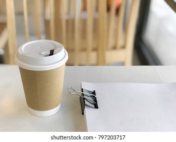 Paper cup with plenty of white notes clamped with black clips on the white table.