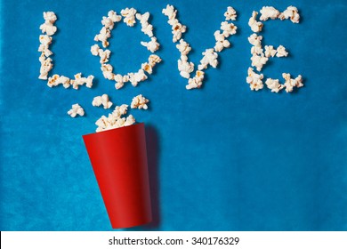 paper cup with popcorn lined word on blue background. mock up. top view.