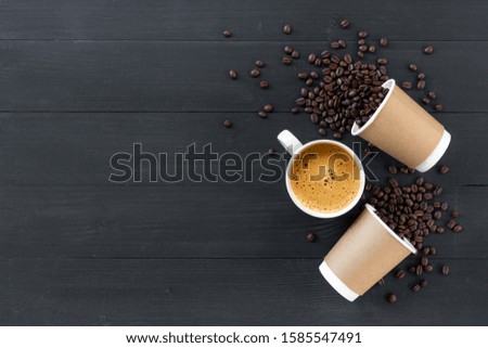 paper cups of coffee and bean on black wooden background. top view