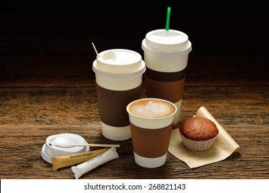 Paper cups of coffee latte and cake on wooden background