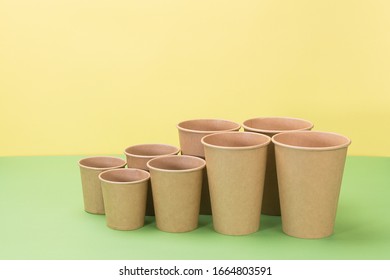 Paper cups in yellow and green background. Ecological utensils.