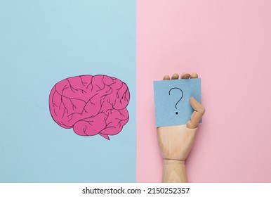 Paper Cut Brain And Memo Papers With Question Marks In Wooden Hand On Pink Background. Finding Answers To Questions. Flat Lay