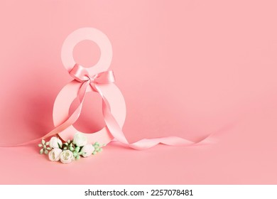 Paper cut eight with ribbon on pink background. Postcard March 8 on a pink background