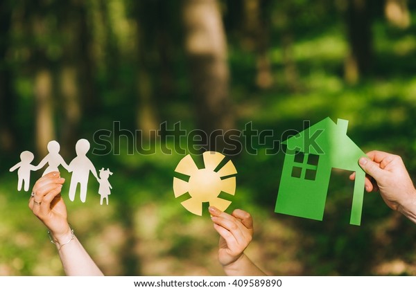 Paper cut\
of family with house and car on green\
grass