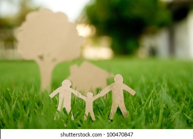 Paper cut of family with house and tree on fresh spring green grass