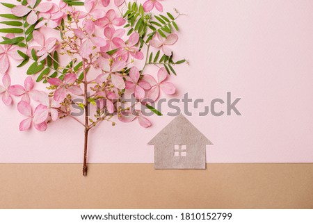 Paper cut house and tree made from flowers, leaves and a tree branch. On pink paper background. Copy space.