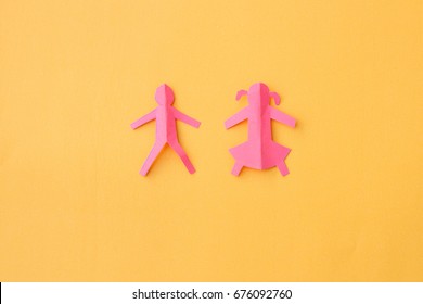 Paper cut outs of boy and girl on yellow background