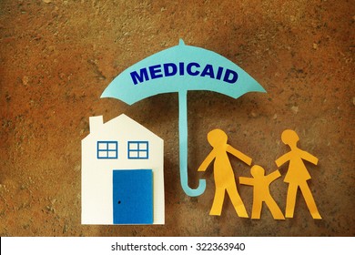 Paper Cutout Family With House Under A Medicaid Umbrella                               