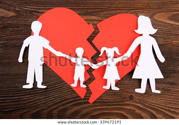 Paper cutout silhouette of a family split apart\
on a paper heart, divorce\
concept