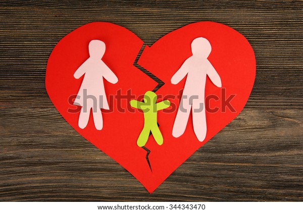Paper cutout silhouette of a family split apart\
on a paper heart, divorce\
concept