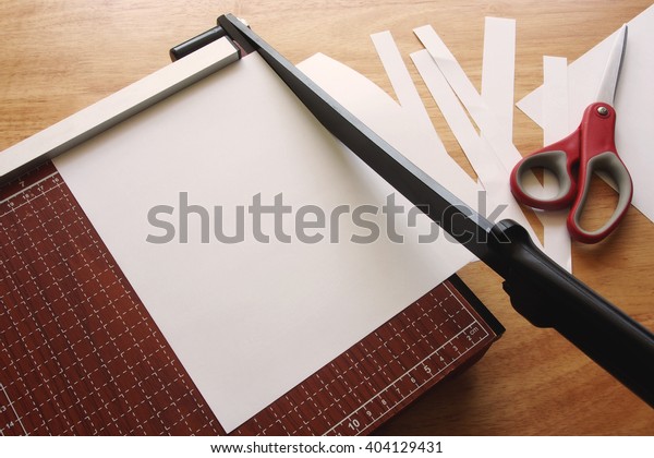 Paper cutter cutting\
paper on wooden desk