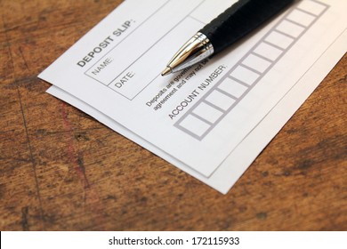 Paper Deposit Slip And Pen Over Wood Background