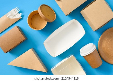 A lot of paper disposable tableware is stacked evenly on a blue background. Use of eco-friendly tableware food delivery. flat lay.