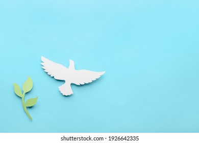 Paper dove and olive branch on color background. International Day of Peace