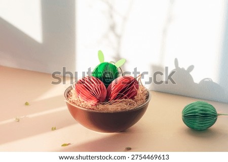 Paper Easter eggs with bunny ears in bowl in sunlight. Closeup.