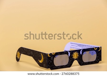 Paper eclipse glasses with sun and crescent moon design on a yellow background