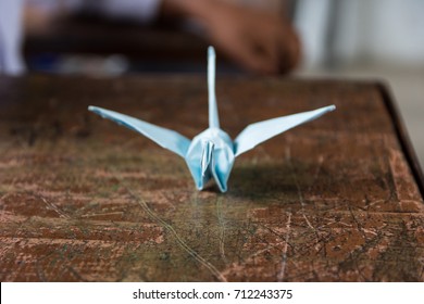 paper folded to make an origami bird on a used wooden school desk