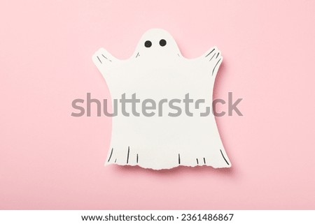 Paper ghost on pink background, top view