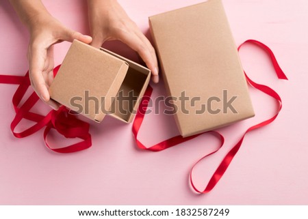 Paper gift box with red ribbon open by hand on pink background, Present for giving in special day, Top view