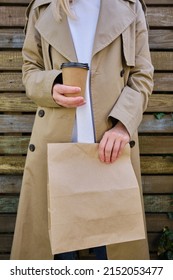 A Paper Glass And A Craft Bag In The Hands Of A Girl. A Glass For Coffee And Hot Drinks To Go. Food Delivery Service. Paper Bag Close Up. Blank Space Mockup For Design, Lettering Or Advertising