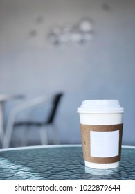 A Paper Glass (one-time) For Coffee Is On The Table. Background Is Blurred. Place For The Inscription On The Glass. Side View With Copy Space