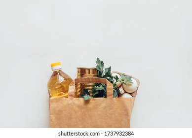 Paper grocery bag with food supplies crisis food supply for quarantine. Eggs, canned food, butter, greens. Food delivery, donation, coronavirus. The view from the top.Copy space - Shutterstock ID 1737932384
