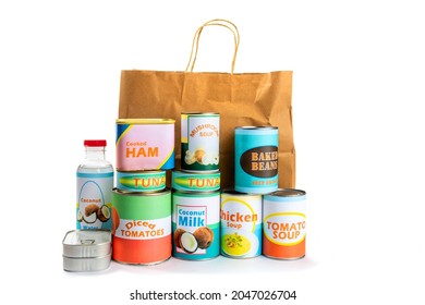 A paper grocery store shopping bag with a variety of fake generic labelled food cans isolated on white 