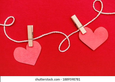 Corazón de papel colgado de fondo rojo. Concepto de día de San Valentín. Piso plano, vista superior, espacio de copia. 