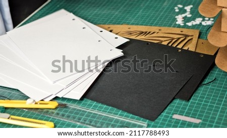 Paper with holes of hole puncher on table in warehouse. Punched paper. Paper for making notebook with interchangeable blocks on rings, hand-assembled