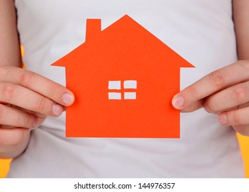 Paper House In Hands On Orange Background