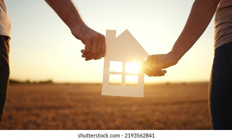 Paper House Happy Family. Friendly Family Hands Holding Paper House The Glare Of The Sun Shine Through The Window A Beautiful Sunset. Mortgage Business Construction Concept Lifestyle. House Dreams