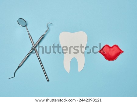 Paper human tooth and dentist medical instruments on blue background, top view