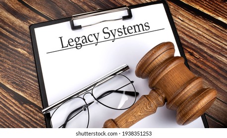 Paper with Legacy Systems with gavel, pen and glasses on wooden background