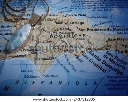 A paper map of the Dominican Republic , with a larimar pendent on top.