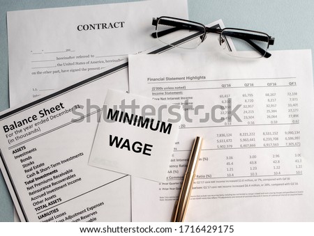a paper with MINIMUM WAGE text on backgrounwith documents and glasses